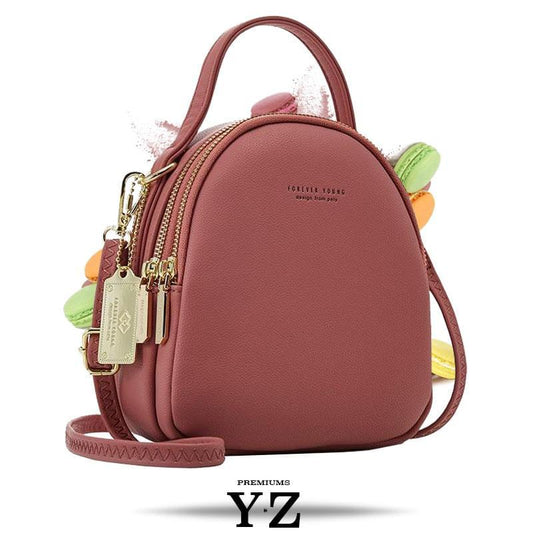Bold and elegant, the wine red macaron is one of our favorites. Made with soft, smooth faux-leather, it features a modern, versatile design that styles up any outfit with effortless elegance. The luxurious golden zippers and tags create a stunning accent against the classy red body. Spacious and practical in its design, this cross-body strapped shoulder bag is perfect for carrying your essentials as you head out for an evening filled with fun, excitement, and adventure.